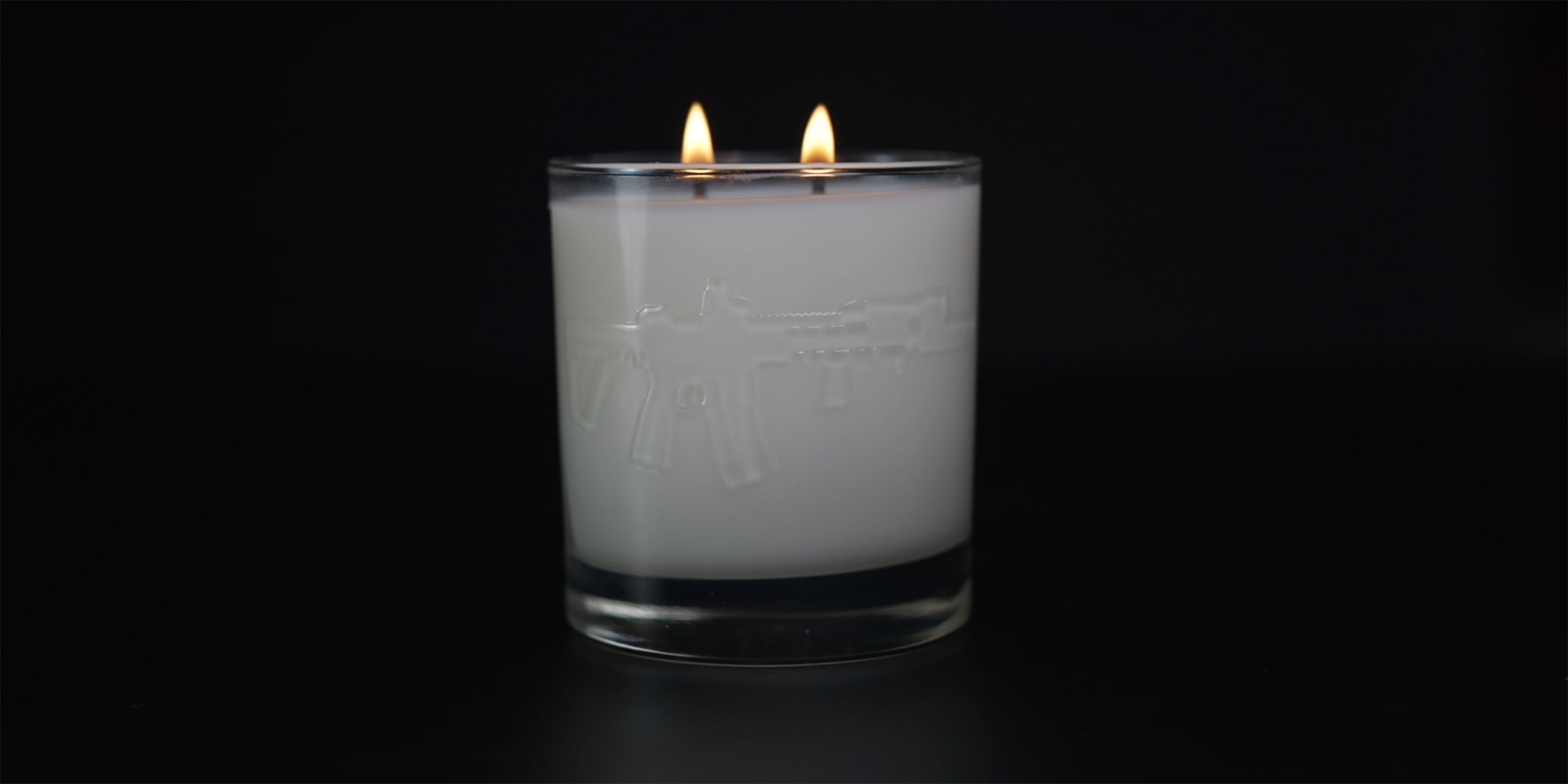 bourbon glass candle, embossed ar15 rifle, lit candle on black background